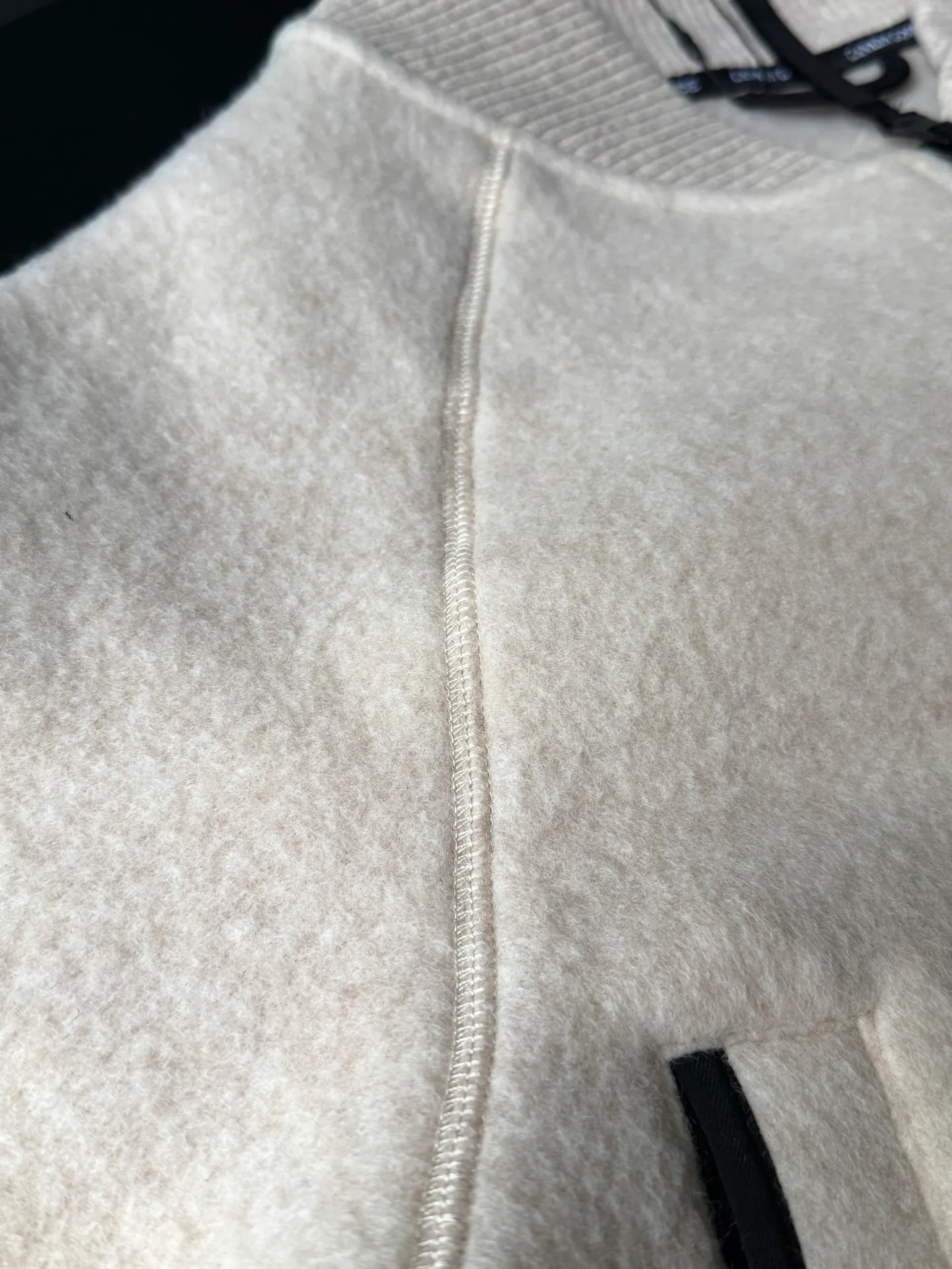 P620 Canada Goose Fleece Wool Baseball Jacket Fabric selection: Wool fleece fabric blended with wool as the main body and a very small amount of spandex and polyester fiber. Wool is a core natural ingredient that provides unparalleled temperature regulation, antibacterial and anti-odor properties and a skin-friendly feel. The feeding of a small amount of spandex gives the fabric a certain degree of four-way elasticity, making it non-restrictive during daily activities. As the basis of fleece's structure, polyester fiber enhances the fabric's durability, wrinkle resistance and quick-drying properties. It contributes to the loft of the fleece and provides functions such as trapping air.  Detail 1: The sleeves and hem are closed with 2×2 ribbing. Its strong elasticity can closely fit wrists and waists of different thicknesses, forming an effective 'seal' to prevent cold wind from blowing back. It can still maintain its original shape after repeated stretching and use, and is not easy to loose and deform. And the ribbed cuffs can convey a sense of design and enhance the visual beauty.  Detail 2: The combination of hood design and elastic buckle improves warmth and windproof performance when wearing. Accessories: Customized elastic drawstring, elastic buckle, custom zipper pendant, custom armband Size: S M L Color: Black Gray Mickey